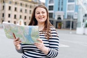 chica tiene un mapa en sus manos. mujer turista estudiar el mapa de ubicación foto