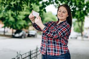Happy young woman on city background making selfie by camera. photo