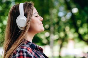 Face profile of a pretty, relaxed woman in headphones on a background of nature, photo