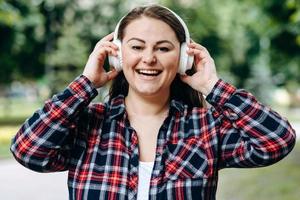 Adorable joven con linda sonrisa usando audífonos contra el fondo de la ciudad foto