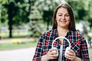 Young, attractive woman holding headphones in her hands, outdoors photo