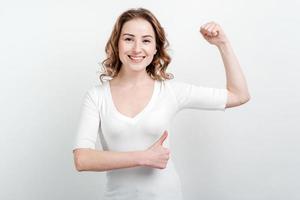 Happy young woman shows her muscles isolated on white background. Strength and power concept photo