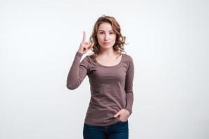 Young girl shows thumb up, gesture to be attentive. photo