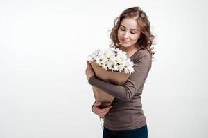 Young girl holding a bouquet of white daisies. White background. photo