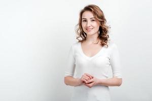 Young woman in white blouse posing in studio on white wall background photo