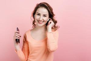 niña feliz disfrutando de la música en airpods en el estudio con pared rosa foto