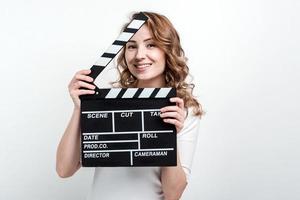 Chica guapa con un tablero de película sobre un fondo blanco.
