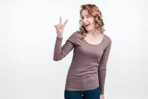 Portrait of a smiling wink woman showing peace gesture isolated over white background photo