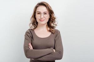 Retrato de mujer con gafas de pie sobre un fondo de estudio cruzó las manos foto