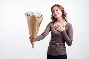 Attractive girl holding a bouquet of chamomile and cute smiling looking at the bouquet photo