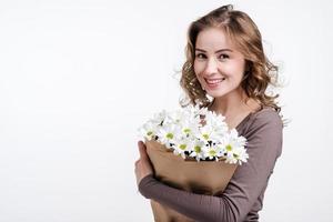 Attractive girl holding a bouquet of chamomiles and cute smiling looking at the camera photo