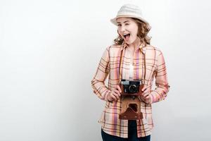 Foto de turista de fotógrafo de mujer joven emocionada de pie sobre fondo blanco sosteniendo la cámara.