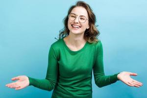 Niña feliz con hermosa sonrisa en vasos sobre fondo azul. foto