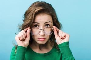 Closeup portrait of pretty   woman in the glasses wearing in green sweater. Looking above glasses photo