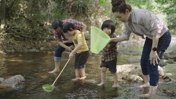 Asian parents teaching their two kids how to catch fishes