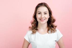 Smiling girl in white t-shirt on pink background. photo