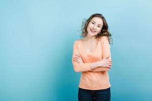 Smiling girl hugging herself.Isolated on blue background. photo