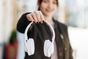 On a blurred background, the girl is clearly visible as a hand holding headphones