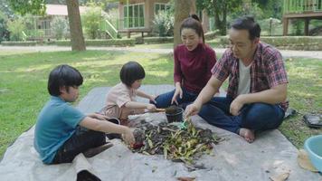 pais asiáticos ensinando seus filhos a fazer adubo enquanto acampam
