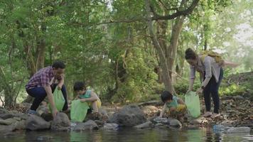 familia asiática recogiendo basura en la naturaleza video