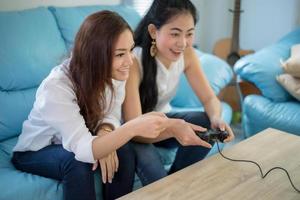 dos mujeres competitivas amigas jugando videojuegos y emocionado feliz alegre en casa foto