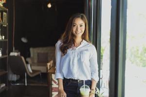 mujeres asiáticas de pie sonriendo y feliz relajándose en una cafetería después de trabajar en una oficina exitosa. foto