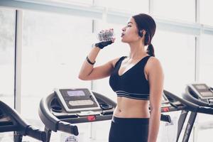 mujer deportiva asia agua potable después de ejercicios en el gimnasio. fitness - concepto de salud foto