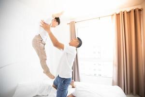 Happy Asian family with son at home on the bedroom playing and laughing photo