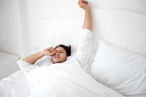 un hombre se despierta en su cama completamente descansado y abre las cortinas por la mañana para tomar aire fresco. foto