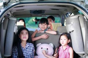 Niña feliz con familia asiática sentada en el coche para disfrutar de un viaje por carretera y las vacaciones de verano en autocaravana foto