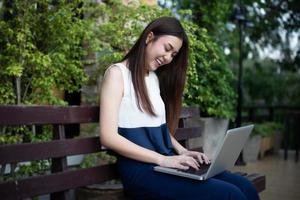 Mujeres de negocios asiáticas que usan el portátil para trabajar al aire libre