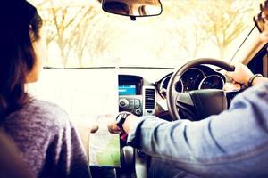 hombre y mujer asiáticos con mapa en viaje por carretera y feliz pareja joven con un mapa en el coche. enfoque borroso y suave foto