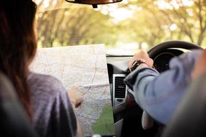 hombre y mujer asiáticos con mapa en viaje por carretera y feliz pareja joven con un mapa en el coche. enfoque borroso y suave foto