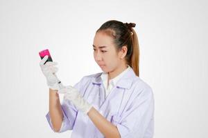 Medical gloved hand holding syringe with red blood liquid and a bead of liquid emerging testing the function of the syringe photo