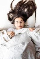 joven y bella mujer morena durmiendo en la cama foto