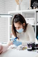 maestro de manicura usando una máquina eléctrica para quitar el esmalte de uñas durante la manicura en el salón foto