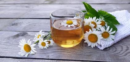 Chamomile aromatic tea in a glass cup on a wooden background photo