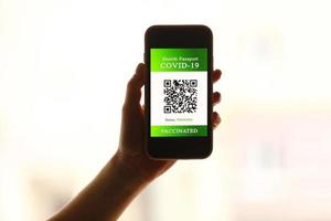 a passport and a smart phone with a certificate of vaccination against the Covid-19 disease. focus on the smart phone. Health Passport concept. travel the world photo