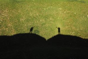 Shadow of lovers on the green hills on summer sunny day. Lovely summer landscape photo