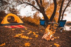 Camping autumn place with bonfire and portable chairs photo