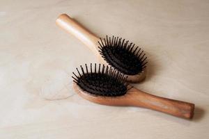 Black hair with wood comb on a wooden table. Concept of hair loss
