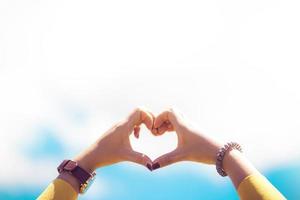 Manos femeninas encuadre en forma de corazón sobre fondo de cielo azul foto