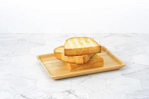 Rebanadas de pan tostado en plato de madera en la mesa