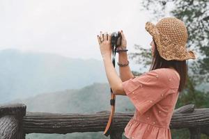 Young beautiful Asian traveler woman using digital compact camera and smile, looking at copy space. Journey trip lifestyle, world travel explorer or Asia summer tourism concept photo