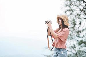 Young beautiful Asian traveler woman using digital compact camera and smile, looking at copy space. Journey trip lifestyle, world travel explorer or Asia summer tourism concept