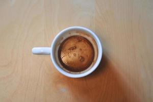 Vista superior de la taza de café vacía después de beber en la mesa de madera foto