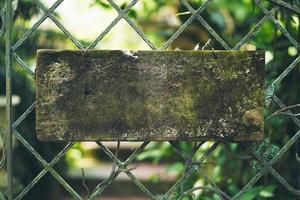 Blank rustic wooden sign hung on a steel fence photo