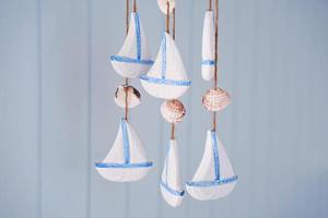 Seashells and sailboat hanging on strings for decoration photo