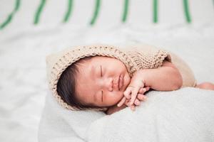 Adorable bebé recién nacido durmiendo pacíficamente sobre una manta blanca foto