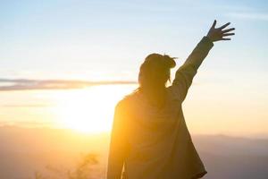 Mujer feliz de pie solo con los brazos levantados durante el hermoso amanecer en la mañana foto